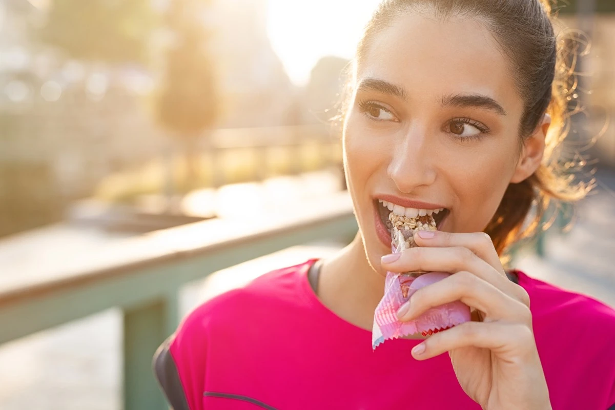 Sporty woman eating protein bar.